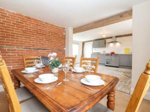 萨克斯曼德姆South Grange Cottage的一间设有木桌和砖墙的用餐室