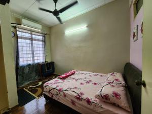 北赖Homestay Taman Pauh Jaya, Seberang Perai, Bukit Mertajam的一间卧室配有一张带粉色床单的床和吊扇。