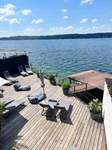 施坦贝尔格湖畔贝格Strandhotel Berg的一个带桌椅的木制甲板和一大片水