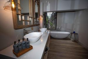 萨比沙禁猎区大象平原猎物酒店的浴室设有2个水槽、浴缸和镜子