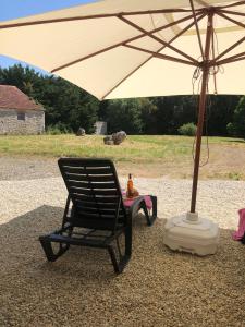 PuyréauxThe charming private Farmhouse at La Grenouillére的一把黑色摇椅,放在伞下
