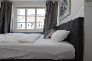 卢塞恩KoBi Apartments Falkenplatz的一张带白色床单和枕头的床,靠窗