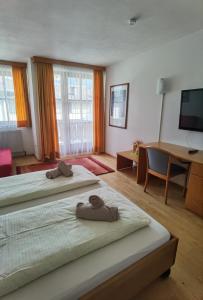 滨湖采尔兰德豪斯泽尔西酒店的一间卧室配有两张床、一张桌子和一台电视。