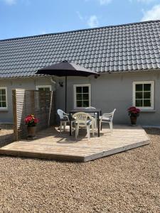 比伦德Apt17 - Guest house just outside of Billund - rural and quiet surroundings的庭院配有桌椅和遮阳伞。