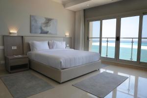 马特鲁港Triumph White Sands Hotel的卧室设有白色大床和窗户。