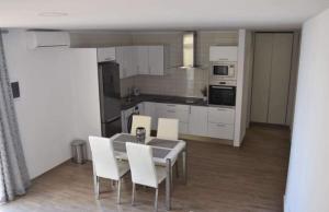 阿德耶paradise beach apartment的厨房配有餐桌和白色椅子