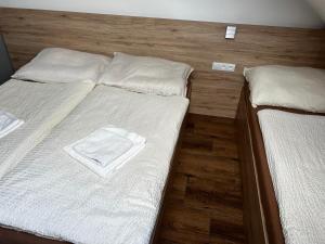 特罗亚诺维采Hotel U Kociana的一间卧室配有两张带白色床单和木地板的床。