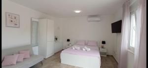 佩特坎内Apartman Punta Radman的白色卧室配有白色的床和粉红色枕头