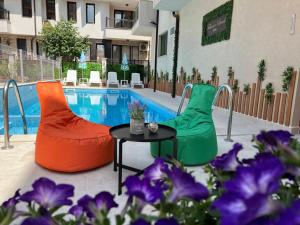 索佐波尔塔巴诺夫海滩酒店的一个带两把椅子和一张桌子的游泳池,并种植了紫色的鲜花