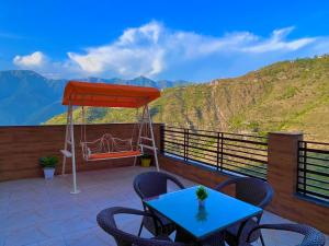 穆索里Doon Valley Resort, Mussoorie的一个带蓝色桌椅和山脉的露台