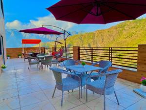 穆索里Doon Nature Valley Resort, Kempty Fall Mussoorie的一个带桌椅和紫色遮阳伞的庭院