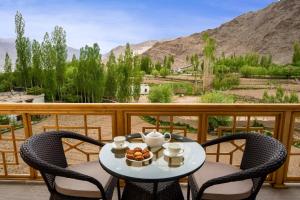 列城Hotel Gyalpo Residency - A Mountain View Luxury Hotel in Leh的阳台上配有桌椅和一碗水果