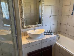 克鲁格斯多普Zacks Country Stay Self-catering的浴室配有盥洗盆、镜子和浴缸