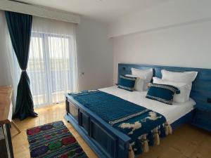 茹里洛夫卡Paradisul Verde的一张蓝色的床,位于带大窗户的房间里