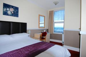 道格拉斯喀里多尼亚酒店的配有一张床、一张书桌和一扇窗户的酒店客房