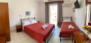 阿莫迪佩拉格斯公寓的一间卧室配有两张带红色床单和白色枕头的床