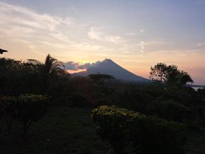 AltagraciaHostel Santa Cruz Ometepe的远处的山,太阳落在后面