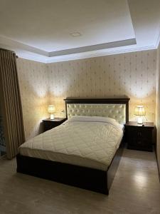 撒马尔罕撒马尔罕拉蒂夫酒店的一间卧室配有一张大床和两个带灯的床头柜。