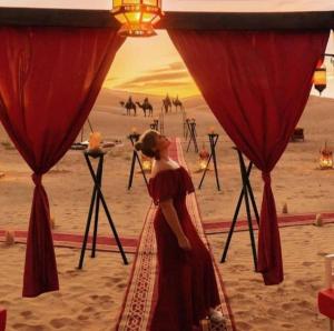梅尔祖卡Merzouga Top Luxury Camp的身着红色衣服站在沙漠中的女人