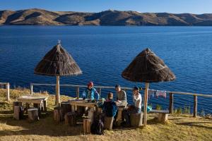 Isla de la LunaWaynapicchu Lodge Isla de la Luna Bolivia的一群人坐在水边的桌子上