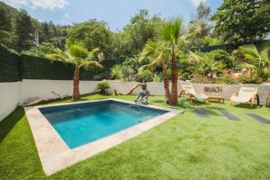 马赛Ô Balinais mini villa avec spa et piscine privatif的一座种植了草地和棕榈树的庭院内的游泳池