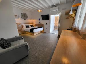 阿诺梅拉Mykonos Double Luxury Mini Suites - Adults only的一间卧室配有一张床、一张沙发和一台电视。
