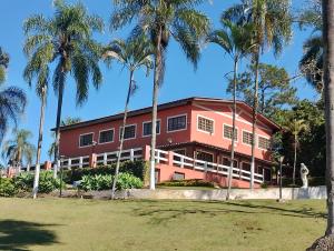 若阿诺波利斯Pousada Solar das Palmeiras的一座红色的建筑,前面有棕榈树