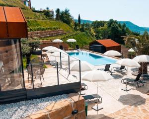 马来济格Wine Paradise - Glamping resort的一座带椅子和遮阳伞的游泳池位于一座建筑旁边