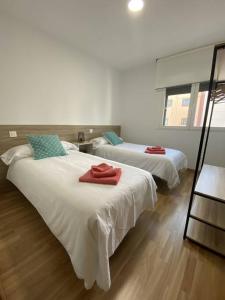 萨莫拉Apartamento NyA Zamora的一间设有两张床铺的房间,配有红色毛巾