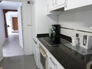 维多利亚-加斯特伊兹San Antonio Suites Vitoria的厨房配有白色橱柜和黑色台面