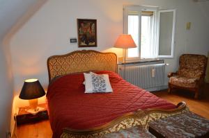 Chez Thérèse et Marguerite的一间卧室配有一张带红色被子和椅子的床