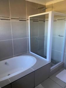 姆巴巴内Waterford Executive Apartments的带浴缸和玻璃淋浴间的浴室。