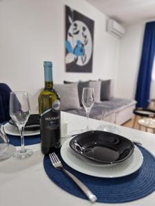 斯雷姆斯卡米特罗维察Apartman Astra的一张桌子,上面放着盘子和一瓶葡萄酒