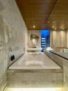 巴西利亚Yolo Motel的石墙浴室内的大型浴缸
