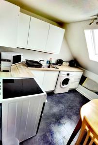 奥克尼Cozy Loft In The Heart Of Kirkwall的厨房配有白色橱柜和洗衣机。
