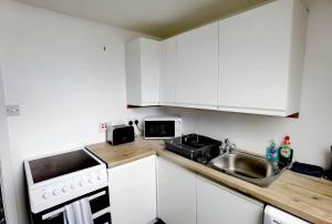 奥克尼Cozy Loft In The Heart Of Kirkwall的小厨房配有白色橱柜和水槽