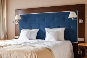 奥尔什丁Villa Garden Dyplomat的一张带蓝色床头板和白色枕头的大床