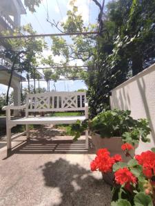 诺维·维诺多尔斯基Apartman Mila的白色长凳,坐在开满红花的庭院