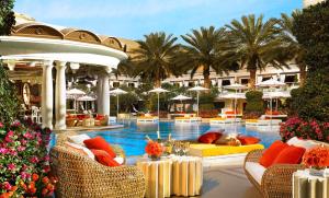 拉斯维加斯拉斯维加斯永利安可酒店的一个带桌椅的度假村游泳池,并种植了棕榈树