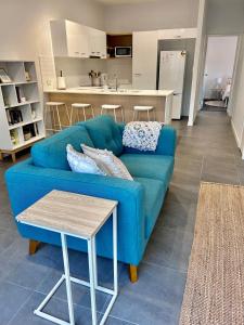布里斯班Unit 1 - Manly Boutique Apartments的一间带蓝色沙发的客厅和一间厨房