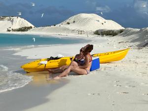 迪弗西Dhiffushi Island Villa的两名妇女坐在海滩上,旁边是一艘黄色的船