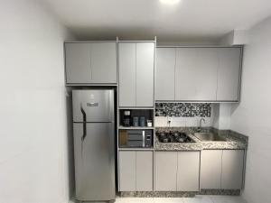 隆德里纳SPAZIO LA VITTA LONDRINA的厨房配有白色橱柜和不锈钢冰箱