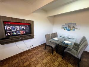 瓜鲁柳斯Ao Lado do Aeroporto com vaga coberta的客房设有桌椅和平面电视。