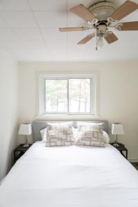DwightMuskoka Waterfront Retreat的卧室配有白色的床和吊扇