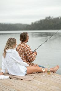 康约拉The Leaning Oak Holiday Lifestyles - Lake Conjola的坐在码头上钓鱼的男人和女人