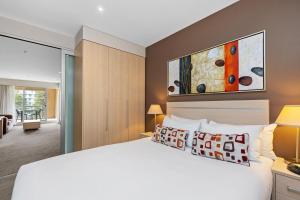 格莱内尔格Belle Escapes - Glenelg Seaside Apartment的一间带白色大床的卧室和一间房间