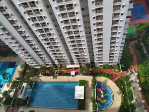 雅加达Spacious & Cozy 27FL - 2BR Apartment West Jakarta的享有带游泳池的大型公寓大楼的顶部景致