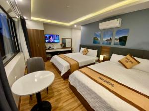 内排NEW SKY AIRPORT HOTEL NỘI BÀI的酒店客房设有两张床和一张桌子。