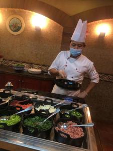 阿可贺巴阿可贺巴假日酒店的厨师站在厨房准备食物