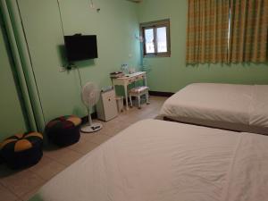 富里里山旅棧民宿 Li Shan Homestay的一间卧室配有两张床、一张桌子和一台电视。